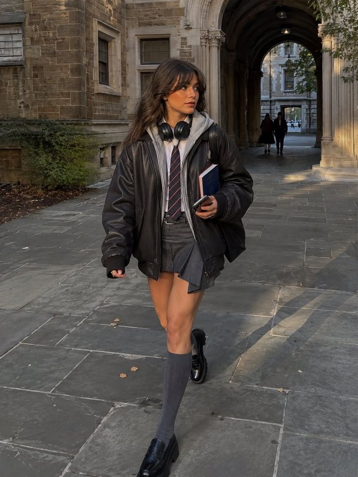 Woman in a school uniform and leather jacket walking on a college campus