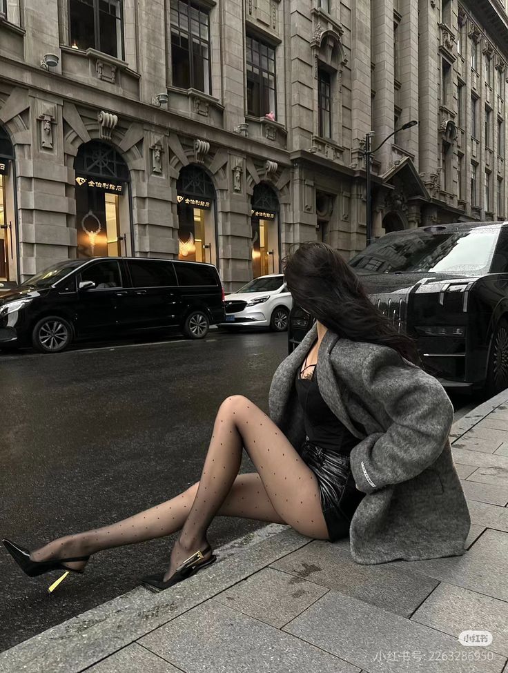 Woman in polka dot tights and a short skirt sitting on a city street