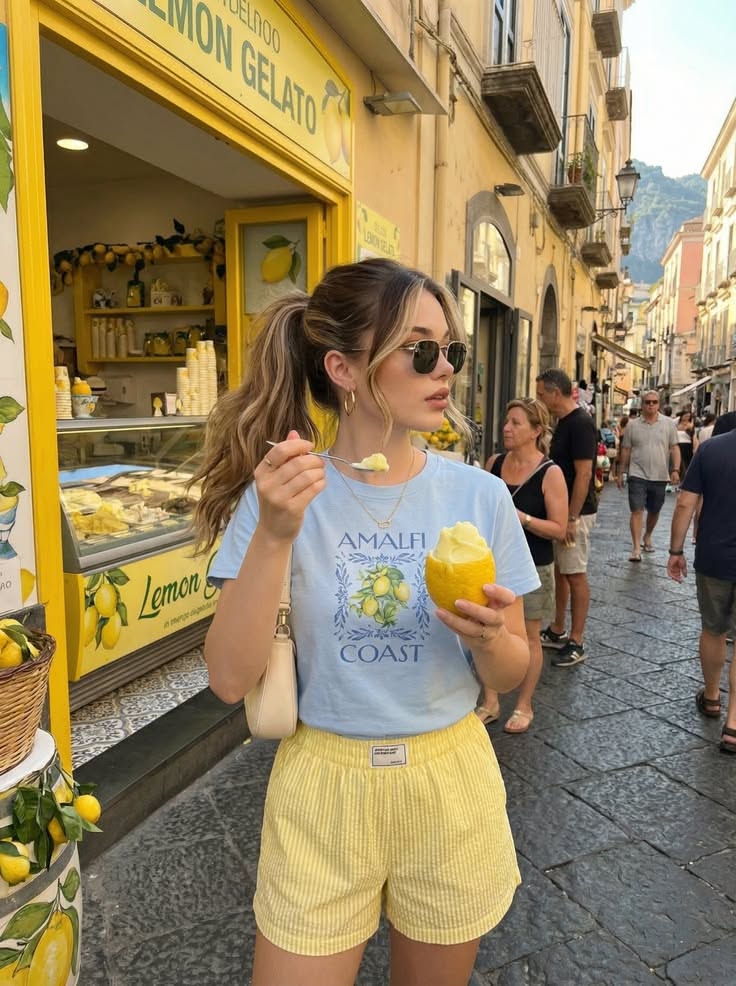 Woman with a ponytail and sunglasses eating lemon gelato on a street