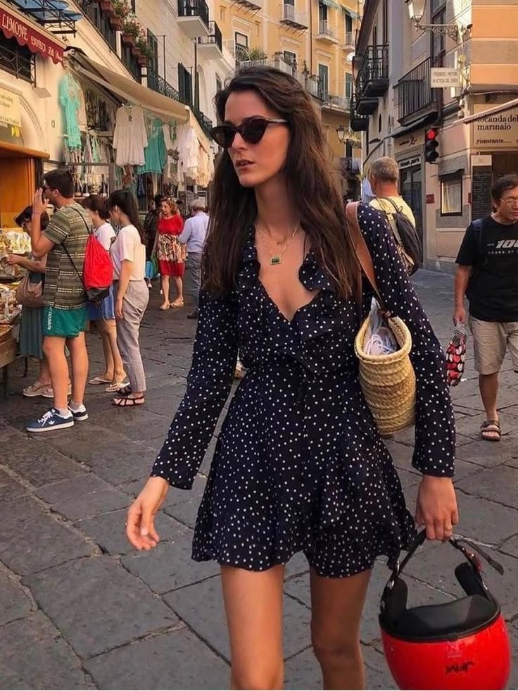 Woman in a polka dot dress and sunglasses walking on a busy street