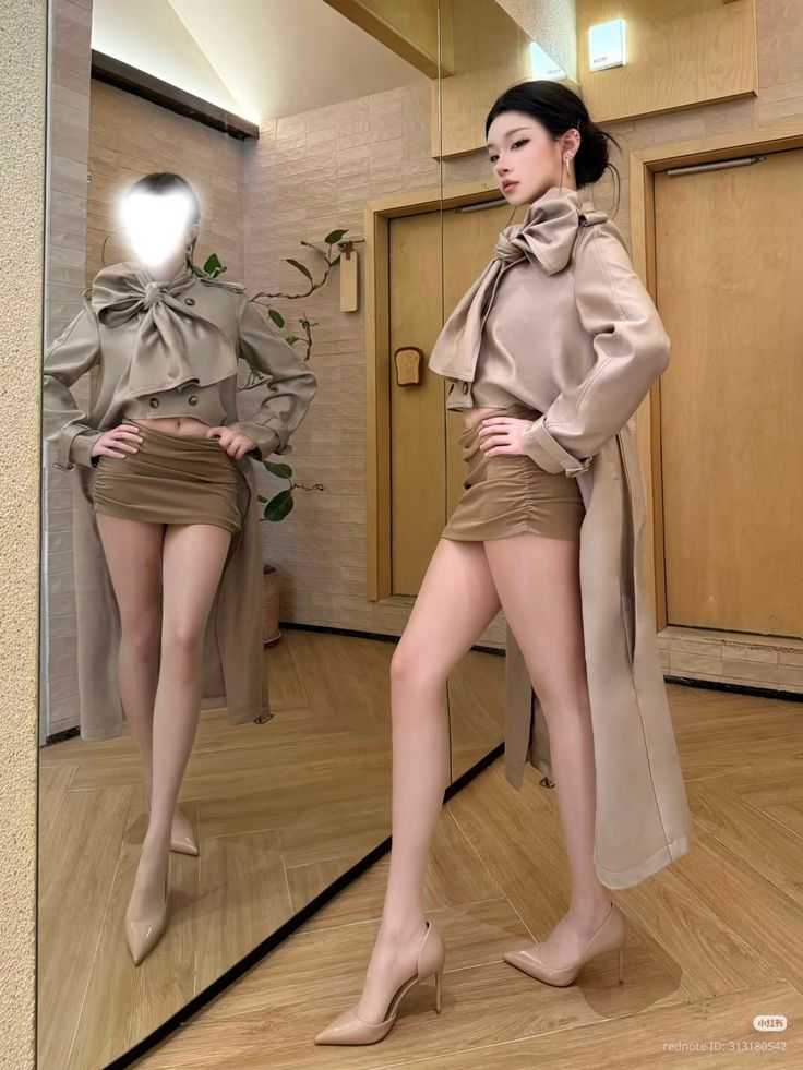 Woman in a long coat and mini skirt posing in front of a mirror