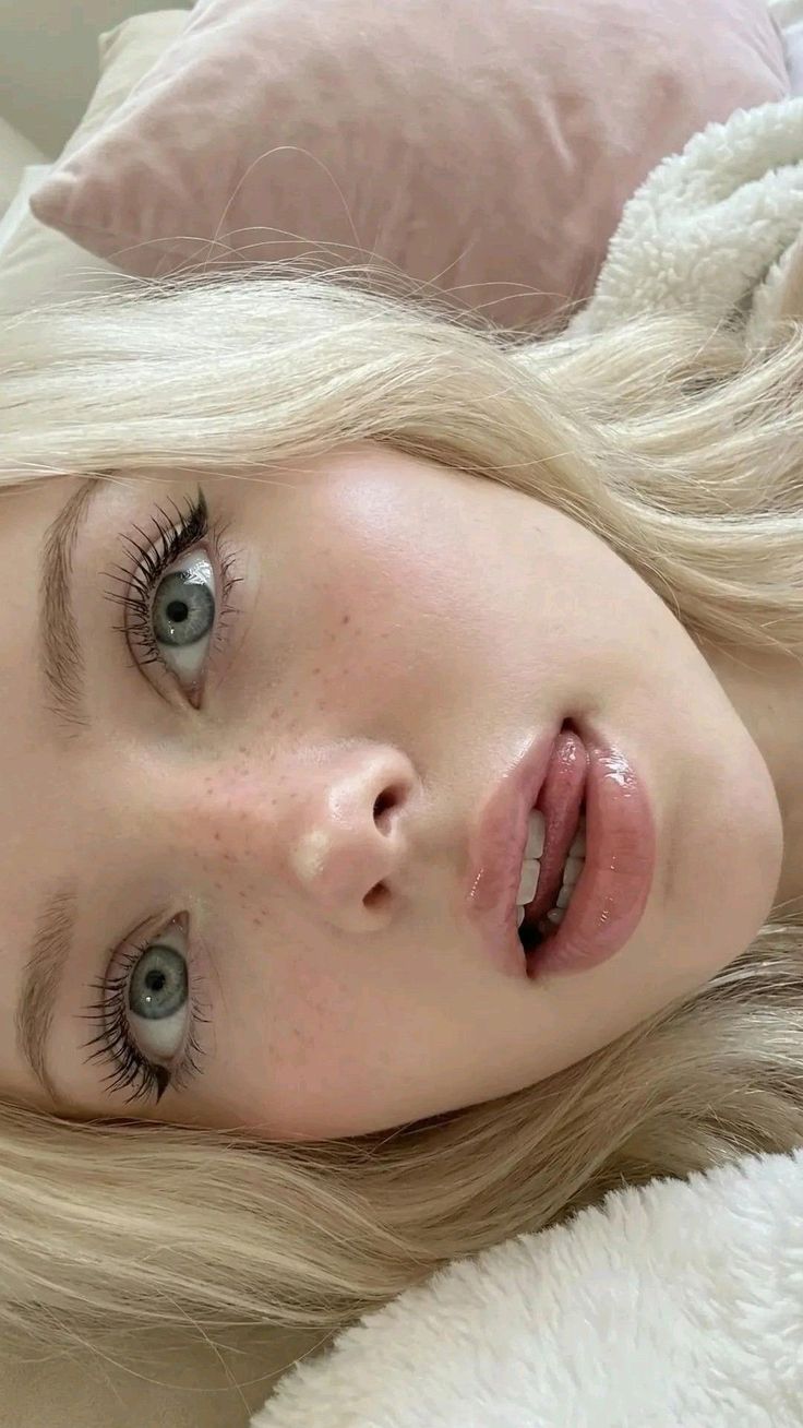 Close up portrait of a blonde woman with blue eyes and glossy lips