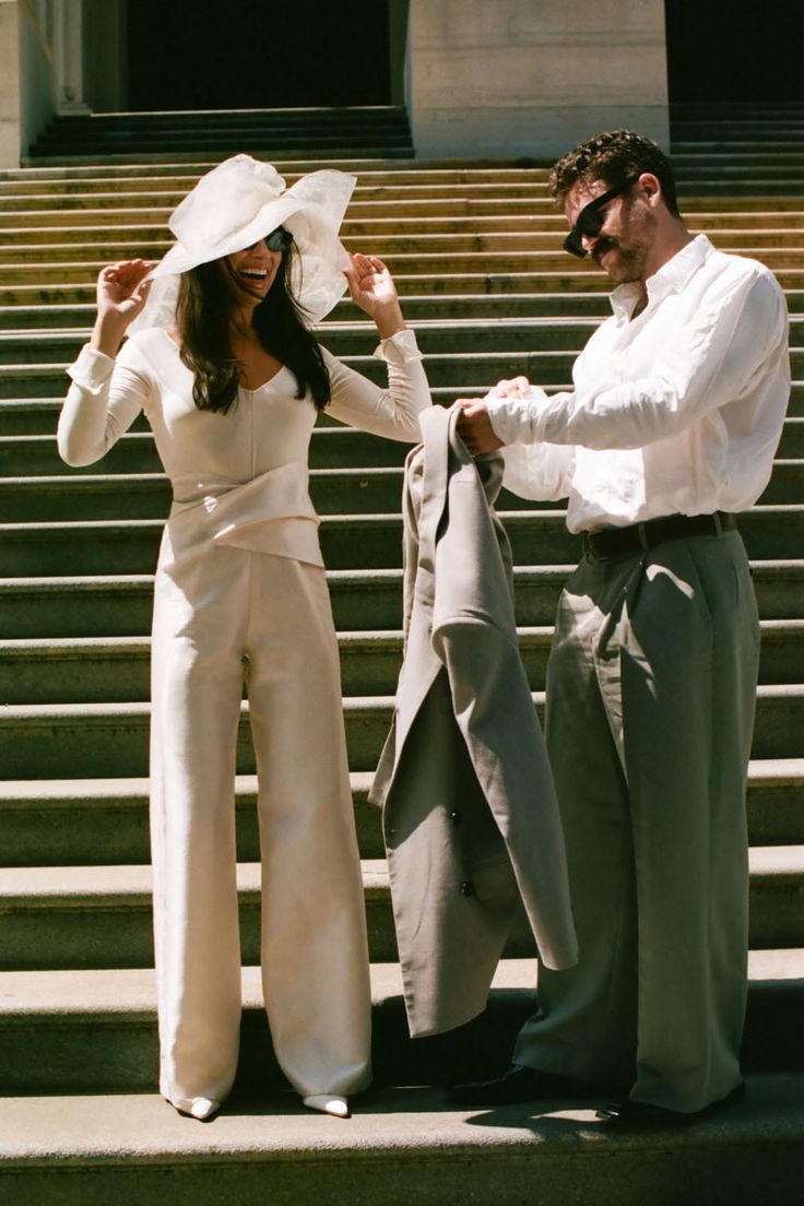 Couple on stairs, woman in wide leg pants and sun hat, man in shirt and trousers