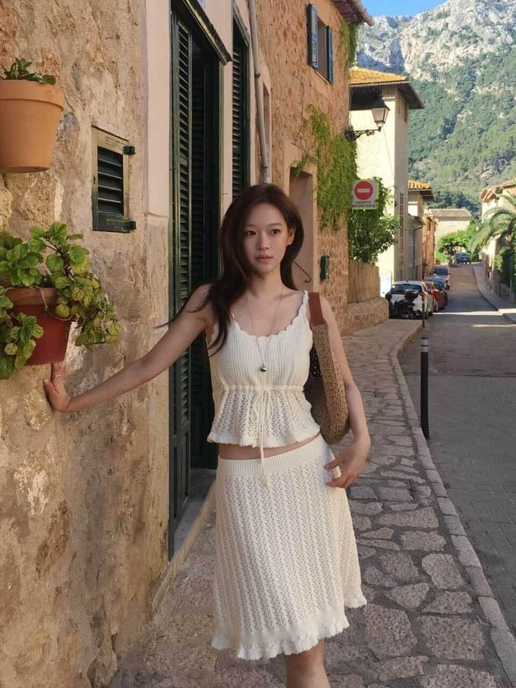 Woman in a white knitted top and skirt on a stone street