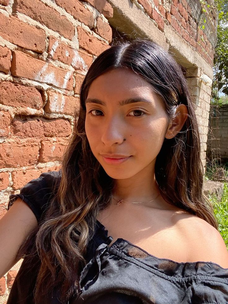 Woman with long hair wearing an off-shoulder black top outdoors