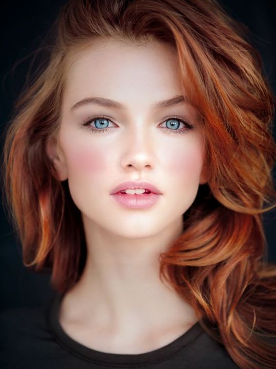 Woman with red hair and blue eyes looking directly at the viewer