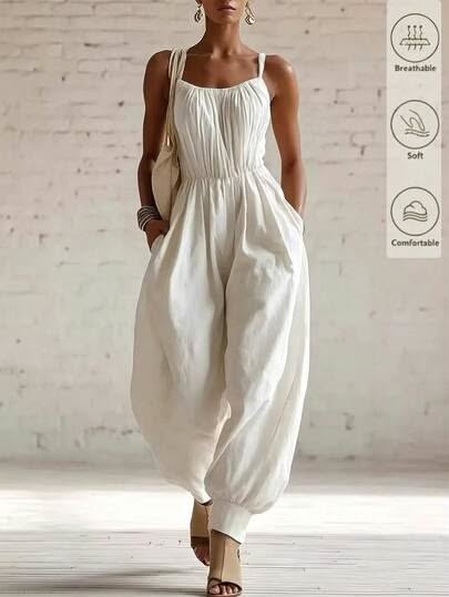 Woman in a white sleeveless wide-leg jumpsuit and sandals indoors