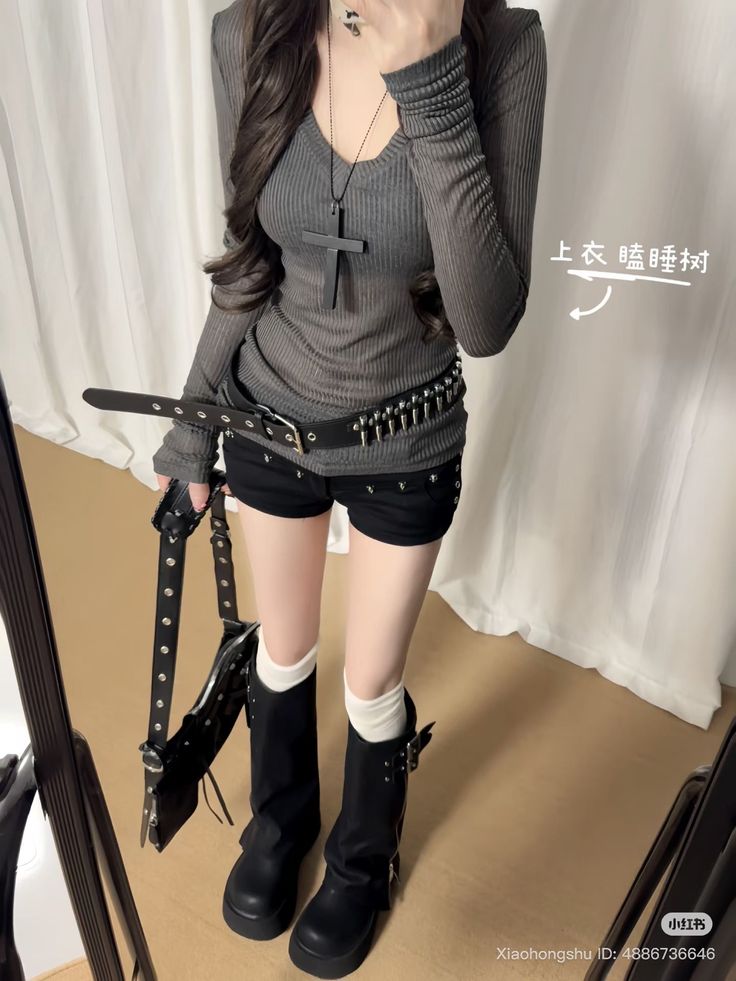 Person in a gray long-sleeve top, black shorts, and platform boots with a cross necklace