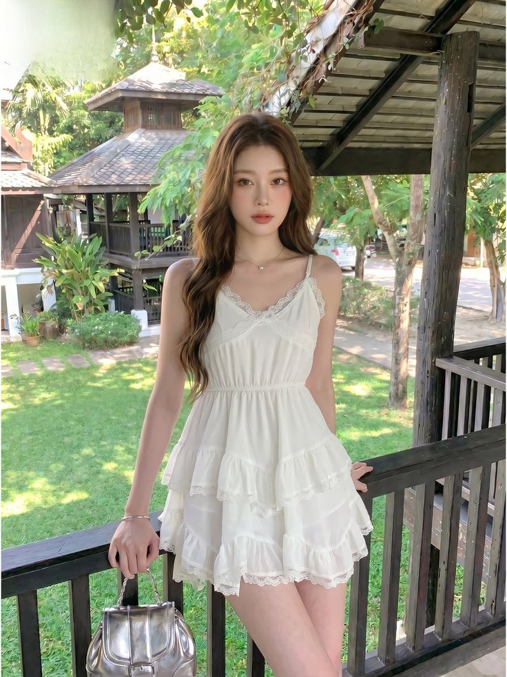 Woman in a white tiered dress standing on a balcony outdoors