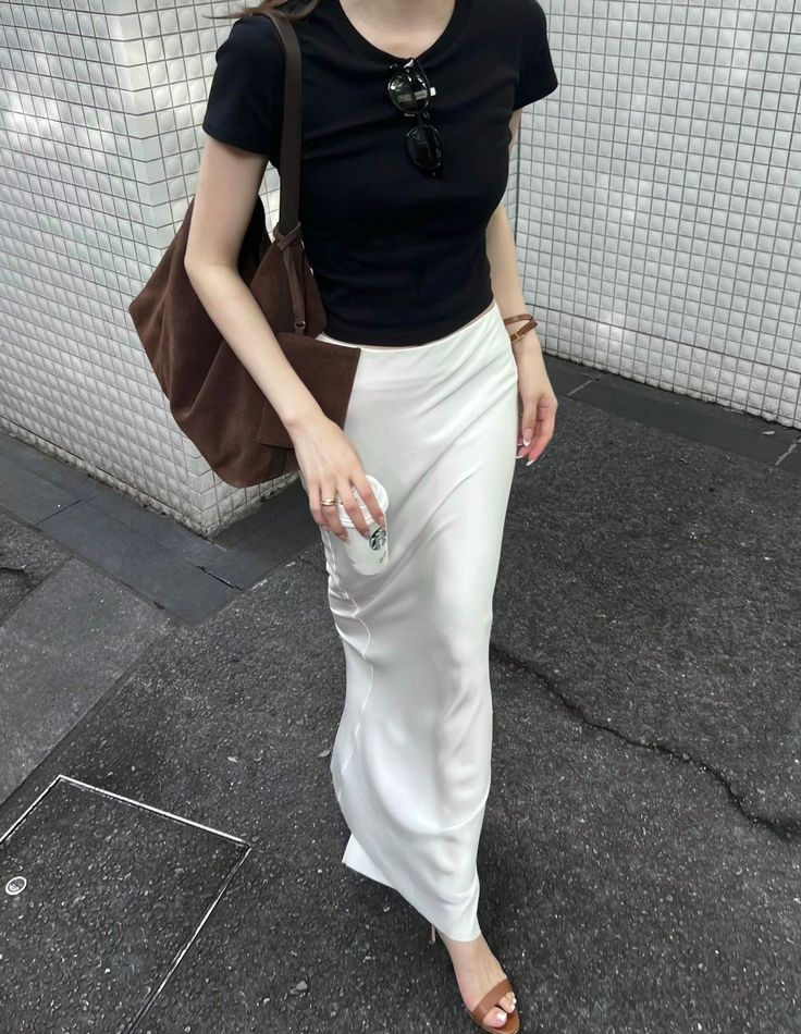 Person in a black t-shirt and white skirt walking on a street