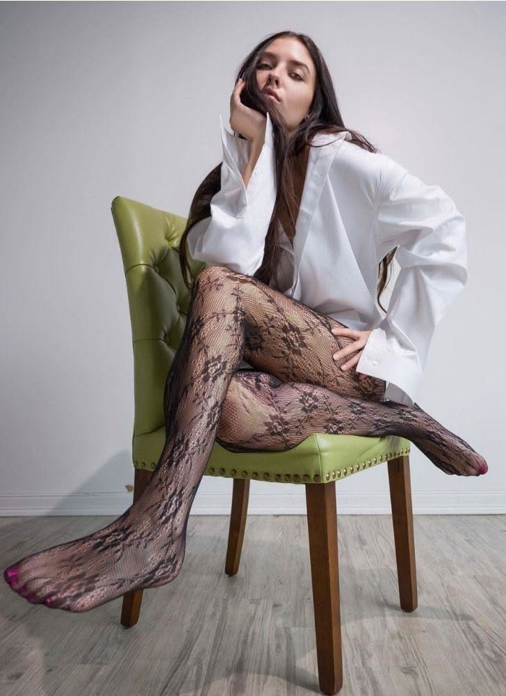 Woman in a white shirt and lace tights sitting on a green chair
