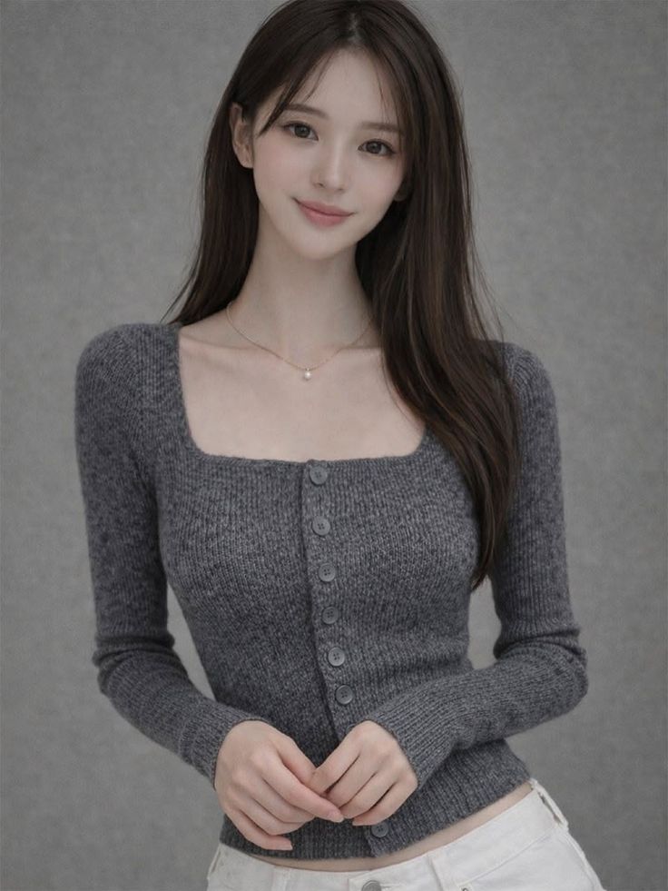 Woman with long hair wearing a gray cardigan and white pants