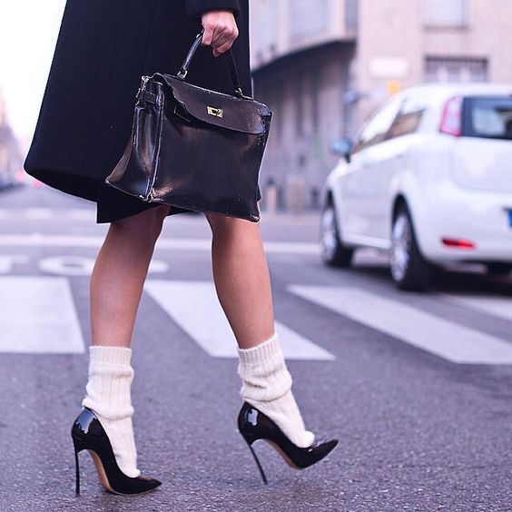 Woman in high heels and leg warmers walking on a street crosswalk