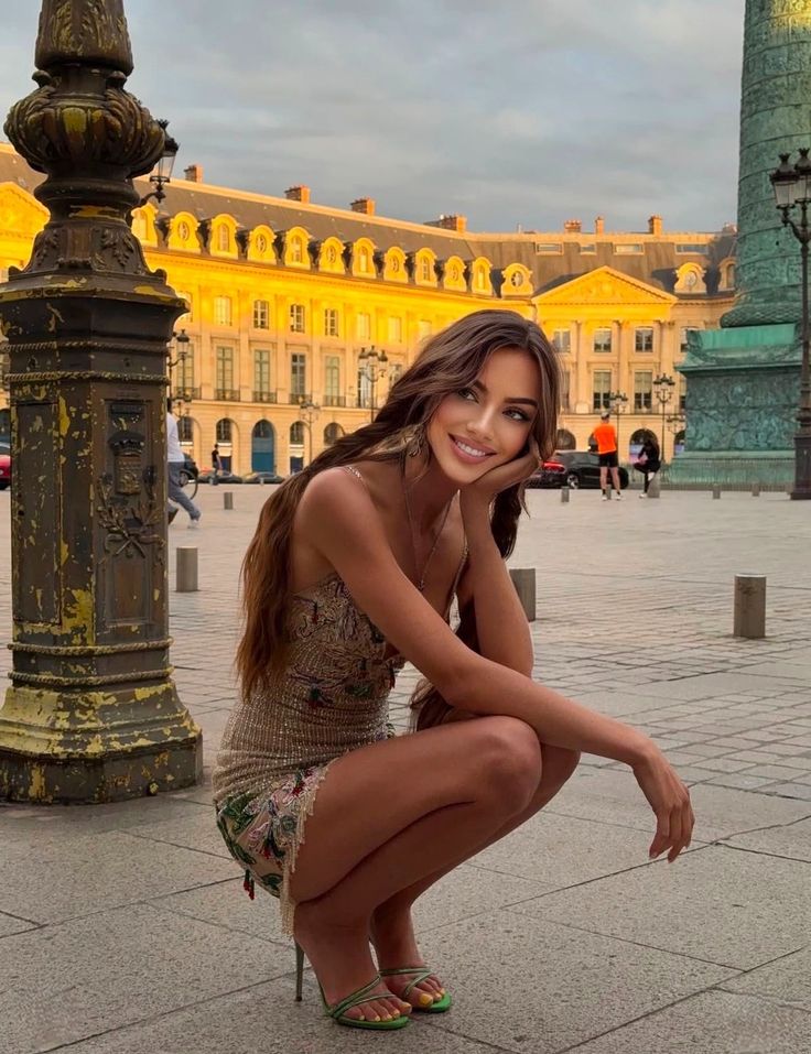 Woman in a mini dress and high heels squatting outdoors at golden hour