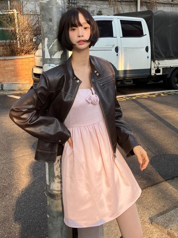 Woman with short hair in a leather jacket and pink dress on a street