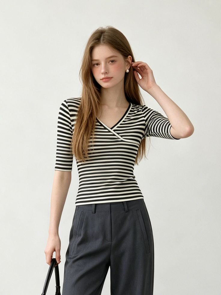 Woman with long hair wearing a striped v-neck shirt and dark pants
