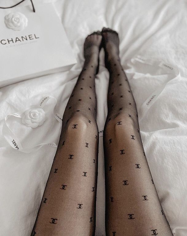 Person's legs in black patterned tights on white bedding