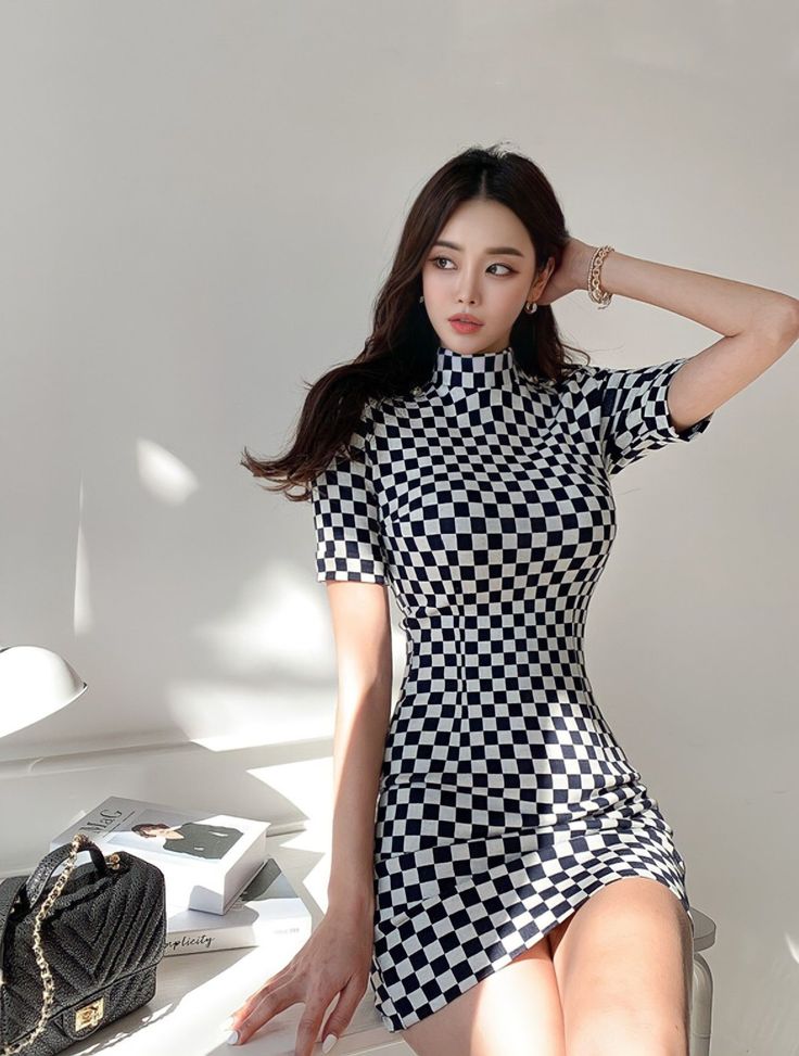 Woman in a black and white checkered dress posing indoors