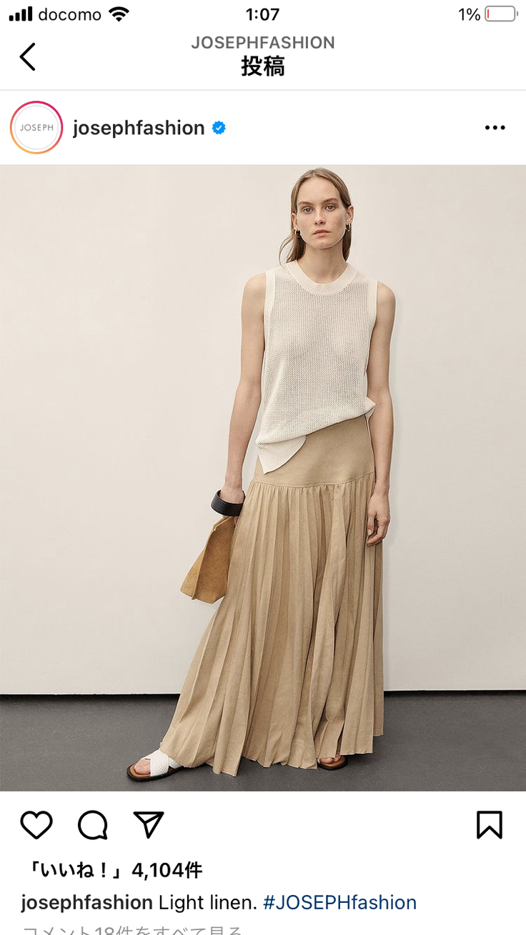 Woman in a sleeveless top and pleated long skirt posing in a studio