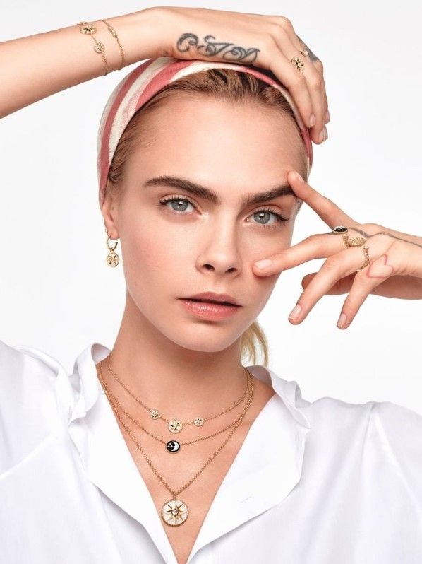 Woman wearing a headband, white shirt, and multiple pieces of jewelry