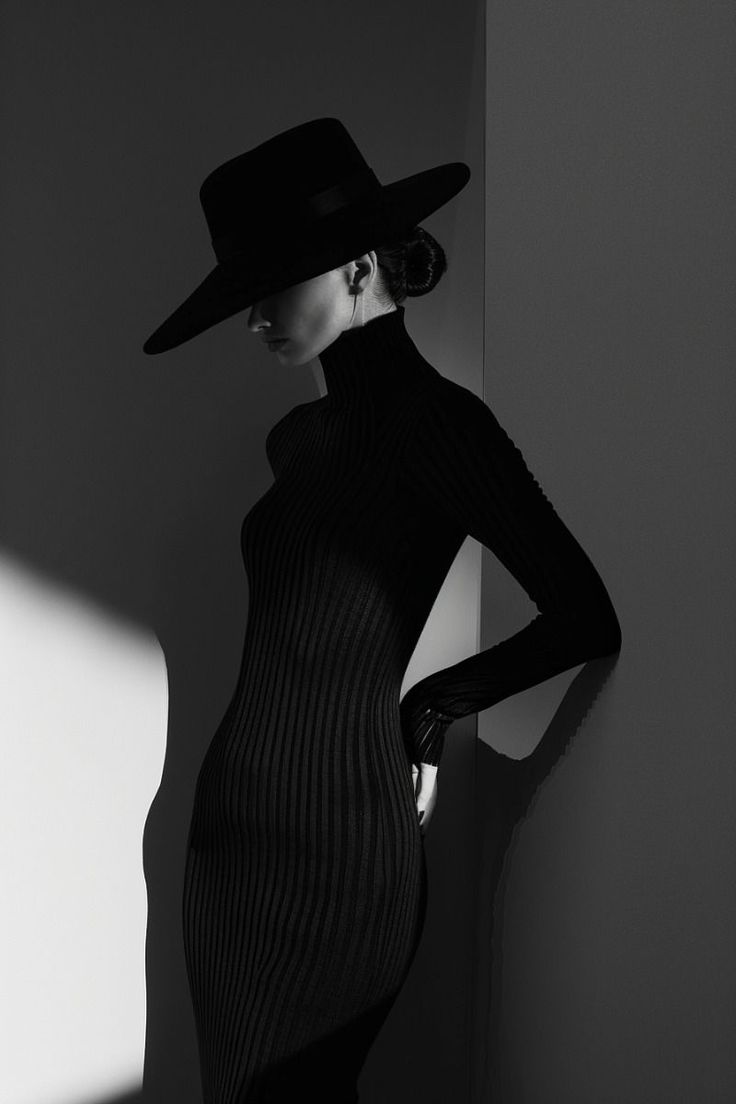 Woman in a black hat and turtleneck dress in dramatic lighting