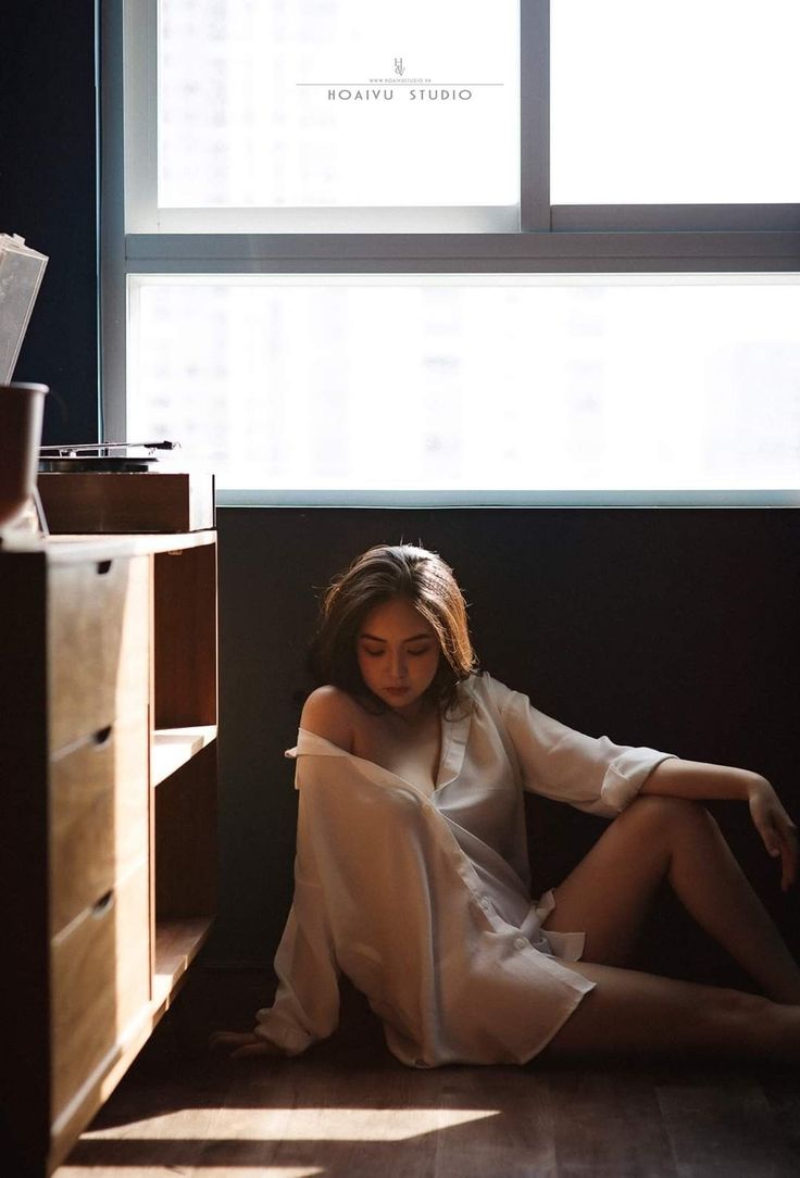 Woman in a white shirt sitting on the floor with soft lighting