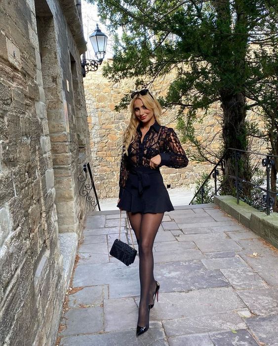 Woman in a black lace shirt and mini skirt walking on a stone path