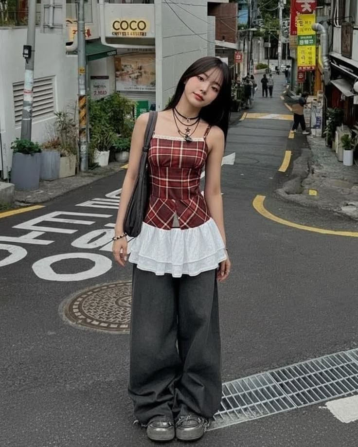 Woman in a plaid top and wide leg pants standing on a street