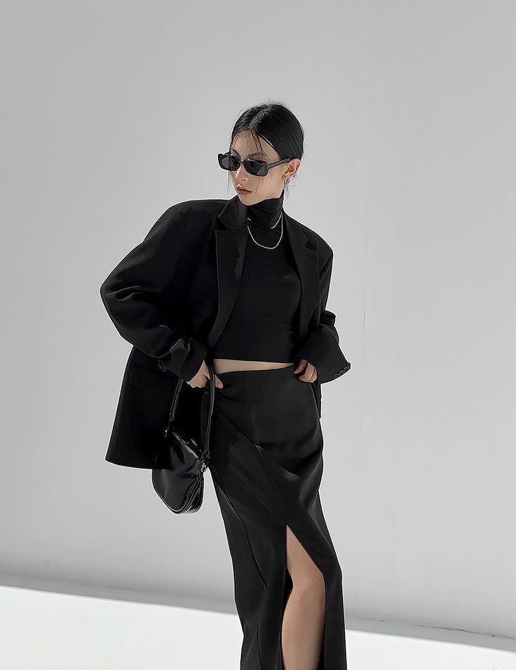 Woman in a black blazer and skirt with a high slit in a studio