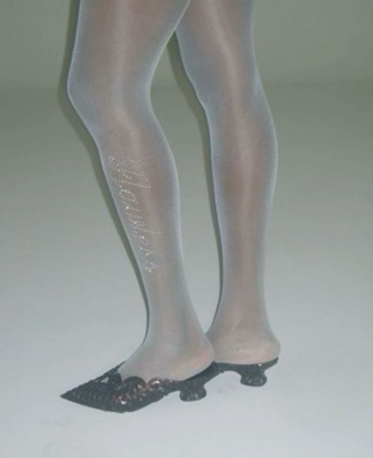 Legs in white tights with sparkling detail and black low-heeled shoes