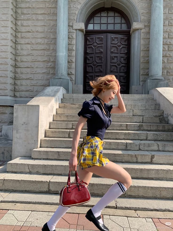 Woman in a plaid skirt and knee-high socks walking up stone stairs