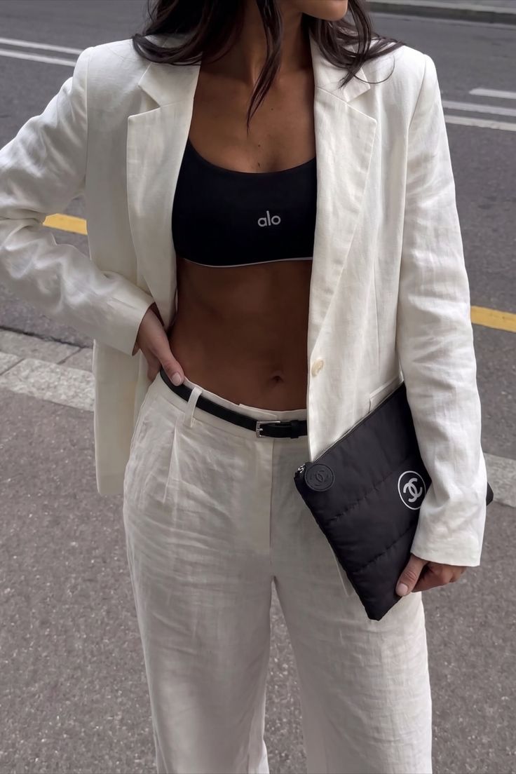 Woman in a white blazer and black sports bra with exposed midriff on a street