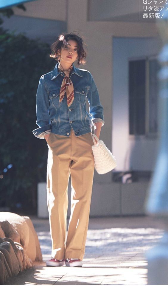 Woman in a denim jacket and khaki pants with a striped scarf and white bag