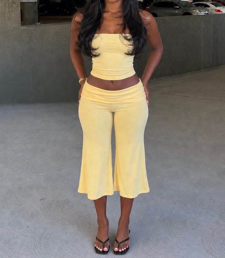 Woman in a yellow two-piece outfit with exposed midriff in an outdoor setting