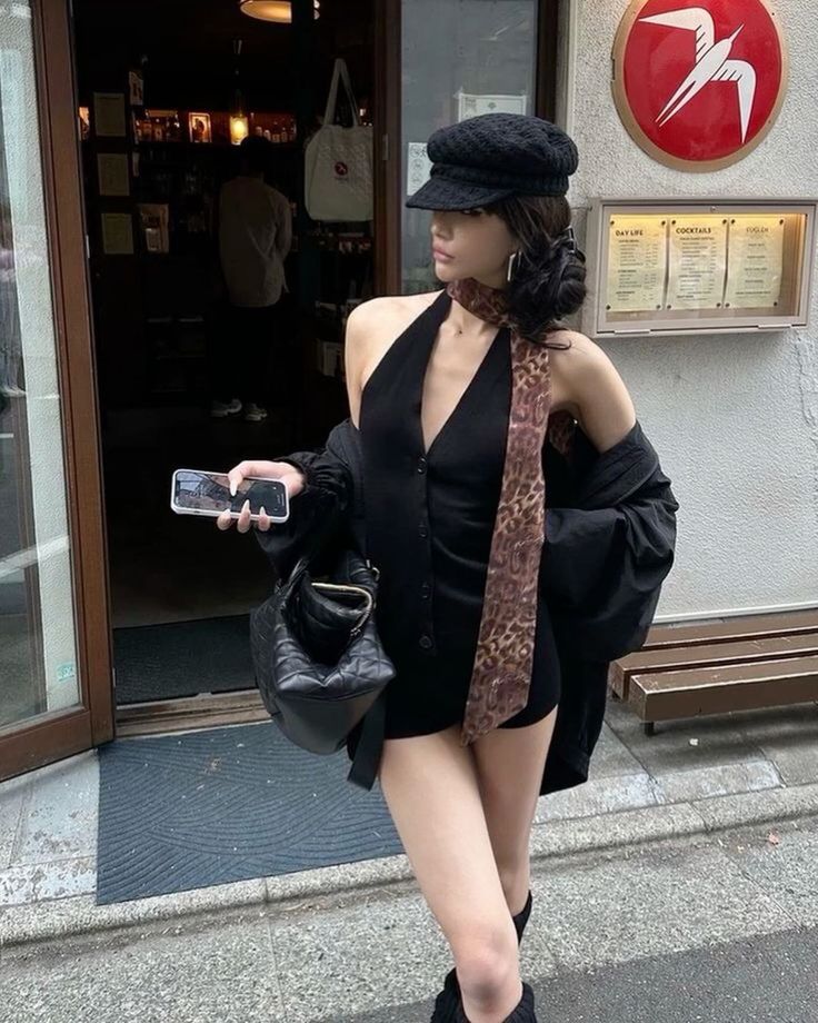 Woman in a black romper and newsboy cap with a leopard print scarf outdoors