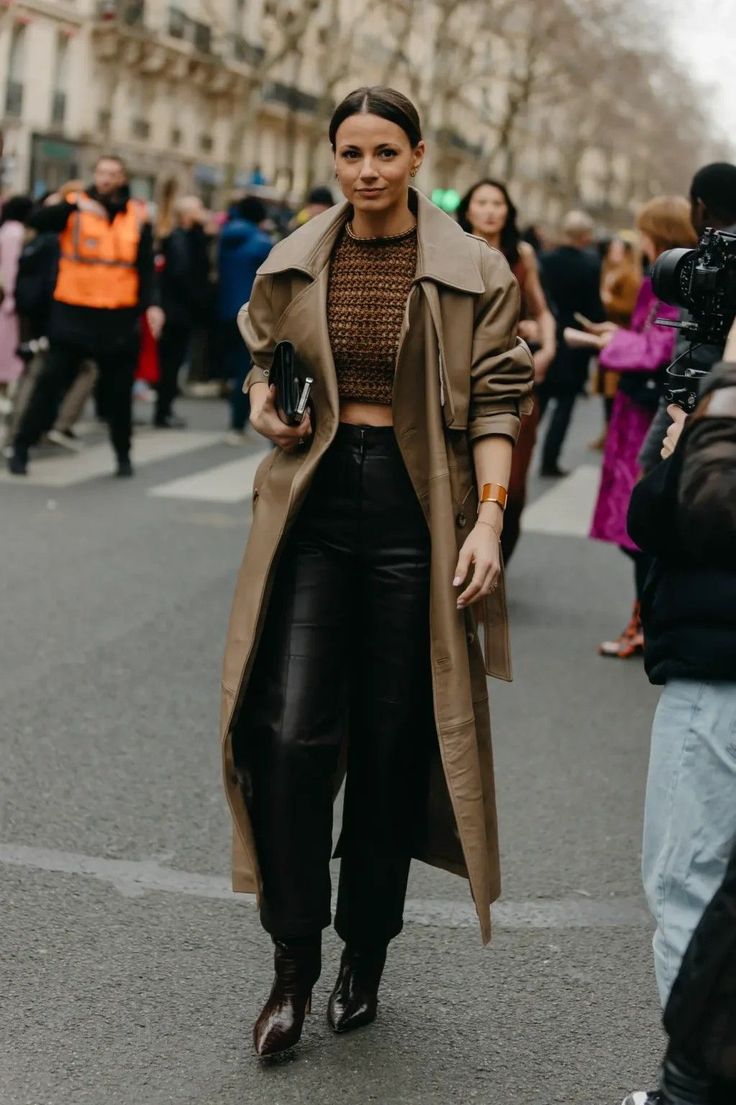 Woman in a trench coat, crop top, and leather pants on a city street
