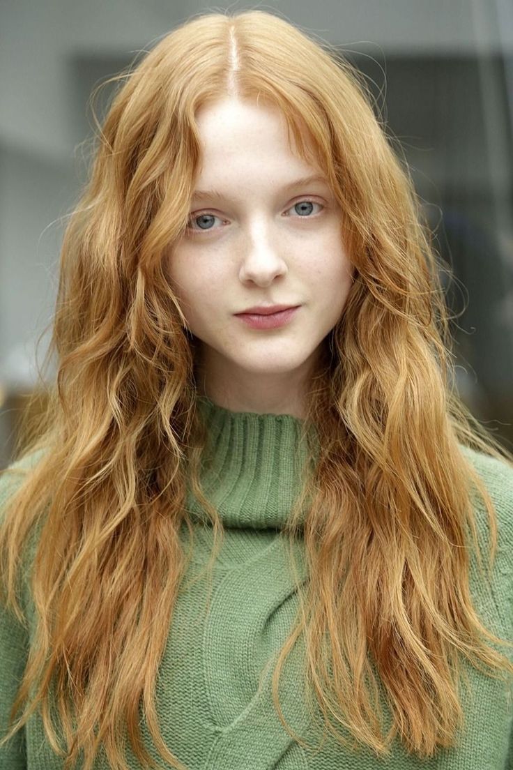 Woman with long red hair and blue eyes wearing a green sweater