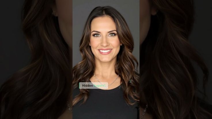 Woman with long wavy hair and green eyes smiling in a studio portrait