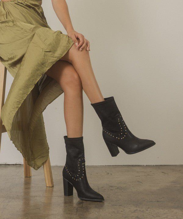Person wearing a green midi skirt and black studded boots while sitting