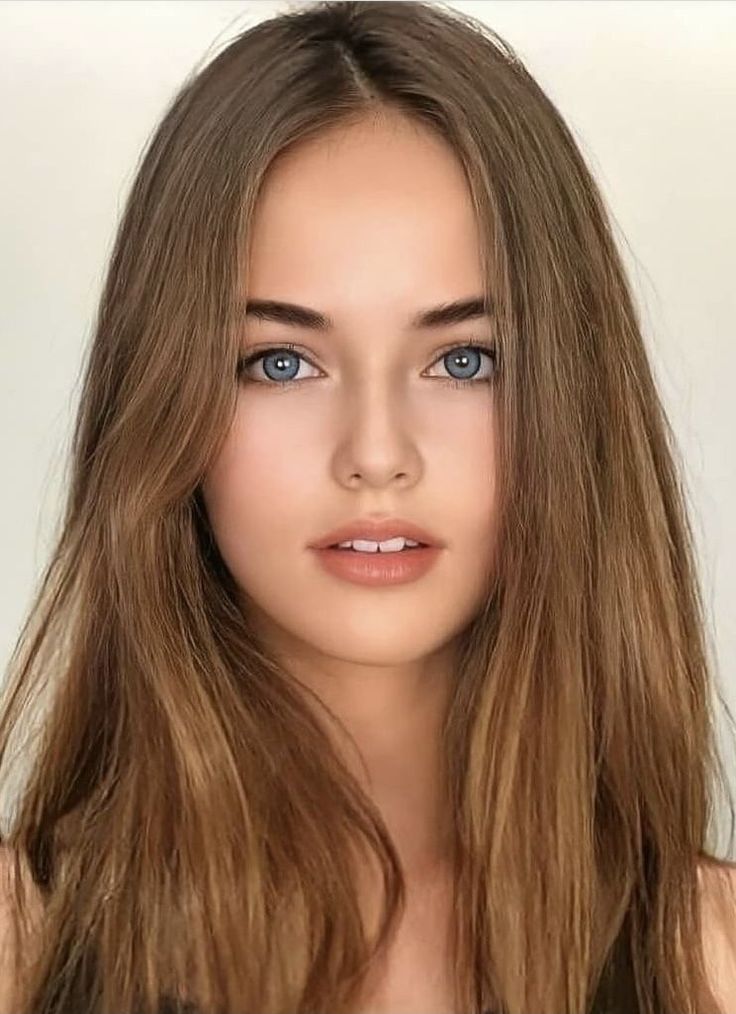 Close-up portrait of a young woman with long brown hair and blue eyes