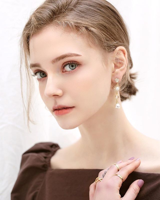 Woman with pearl earrings and gold rings wearing an off-shoulder top