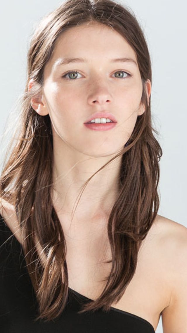 Woman with long brown hair and green eyes wearing a black top