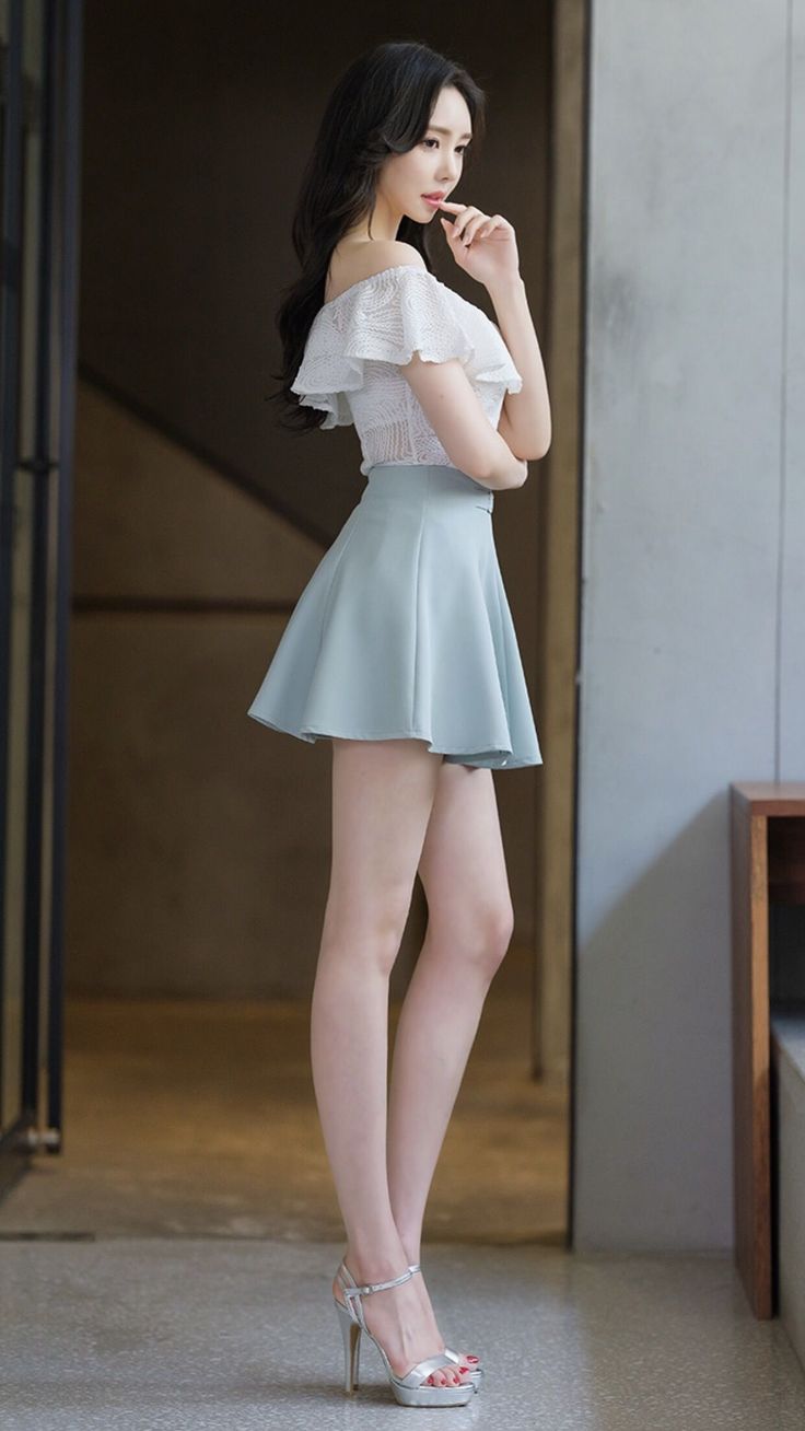 Woman in an off-shoulder top and mini skirt posing indoors