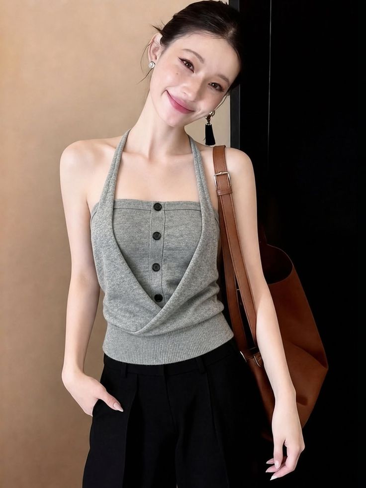 Woman in a gray halter top and black pants with a brown bag