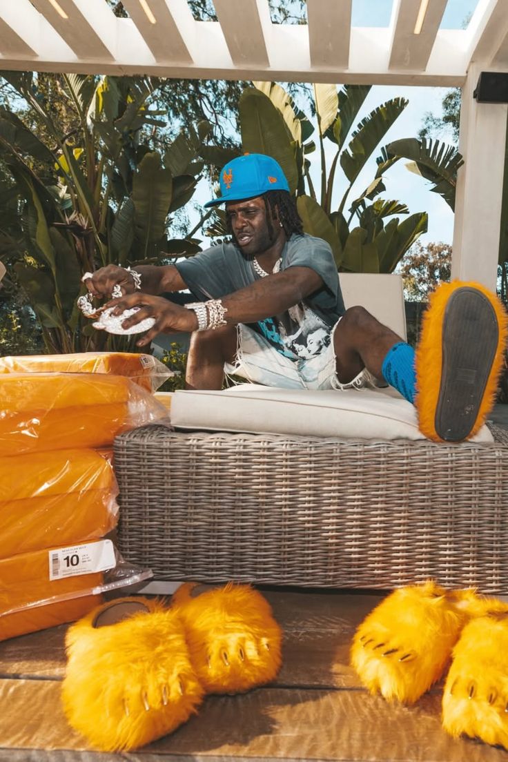 Man with dreadlocks and a blue cap wearing bear paw slippers outdoors