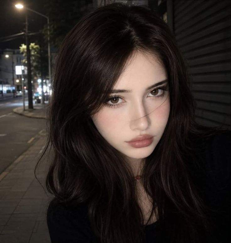 Woman with long dark hair on a street at night