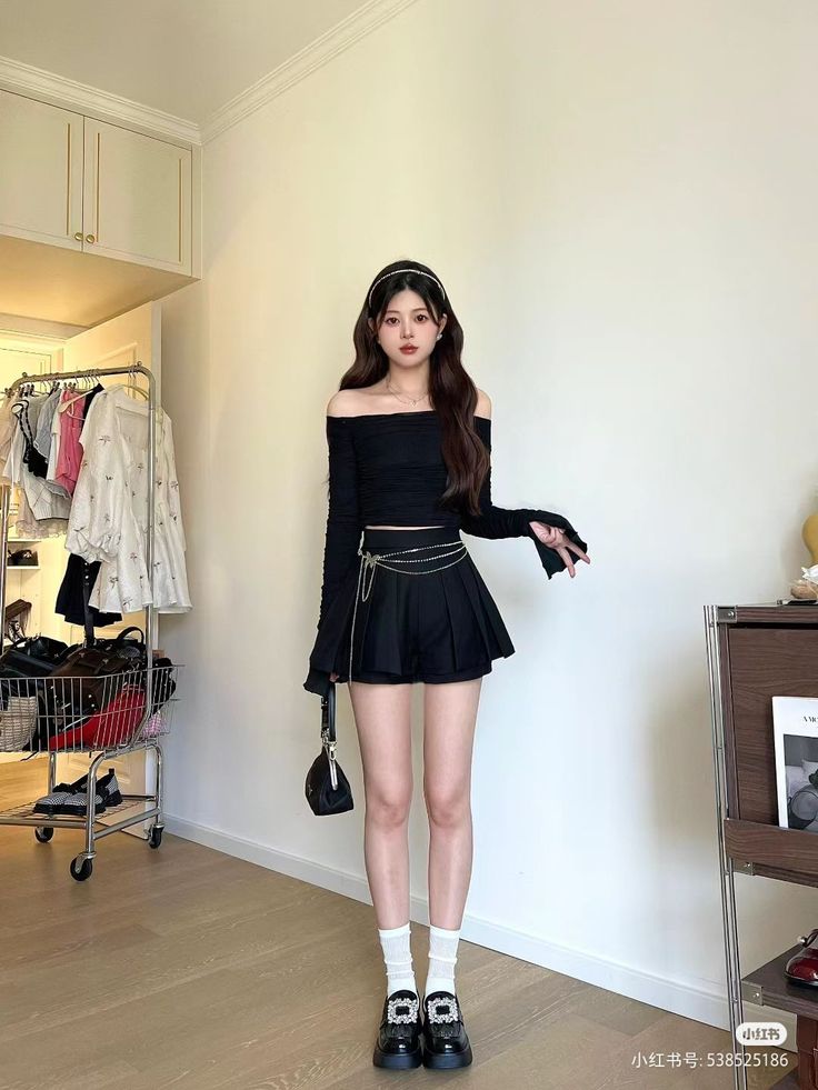 Woman in a black off-shoulder top and pleated skirt indoors