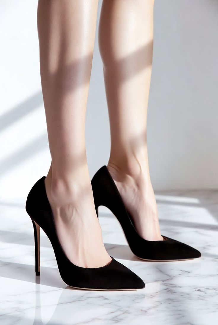 Woman's legs in black high heels on a marble floor with soft lighting