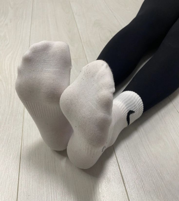 Person wearing white socks and black leggings on a light wooden floor