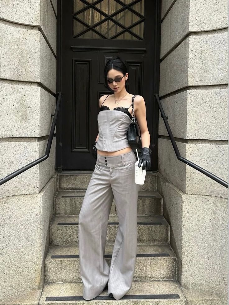 Woman in a corset top and wide leg pants standing on stone steps